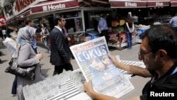 A lottery ticket vendor reads a Turkish newspaper published with an headline reads "downfall" and a portrait of Turkey's President Tayyip Erdogan in Ankara, June 8, 2015. 