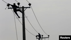 FILE - Employees from electricity board pull electric cables on top of electricity posts near a newly built road in Piliyandala, Sri Lanka, Nov. 29, 2016. 