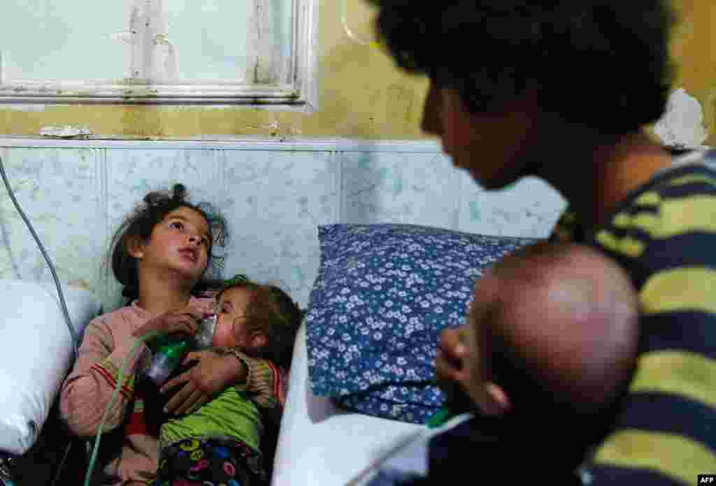 A Syrian girl holds an oxygen mask over the face of an infant at a make-shift hospital following a reported gas attack on the rebel-held besieged town of Douma in the eastern Ghouta region on the outskirts of the capital Damascus, Jan. 22, 2018. At least 21 cases of suffocation, including children, were reported.