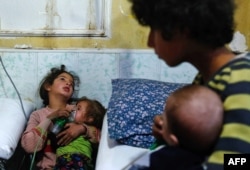 A Syrian girl holds an oxygen mask over the face of an infant at a make-shift hospital following a reported gas attack on the rebel-held besieged town of Douma in the eastern Ghouta region on the outskirts of the capital Damascus, Jan. 22, 2018.