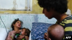 A Syrian girl holds an oxygen mask over the face of an infant at a make-shift hospital following a reported gas attack on the rebel-held besieged town of Douma in the eastern Ghouta region on the outskirts of the capital Damascus on January 22, 2018. 