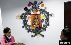 Women speak in front of a painting depicting a pregnant woman wearing a tear gas mask at the Mayor's offices of Barinas, in Barinas, Venezuela, June 14, 2017.