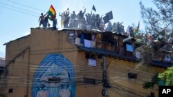 Reclusos levantan banderas y pancartas mientras participan en una protesta en la cárcel San Sebastián, en Cochabamba, Bolivia, exigiendo mejores condiciones sanitarias.