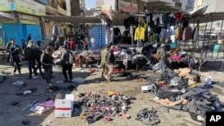 FILE - People and security forces gather at the site of a deadly bomb attack in a market selling used clothes, in Baghdad, Jan. 21, 2021.