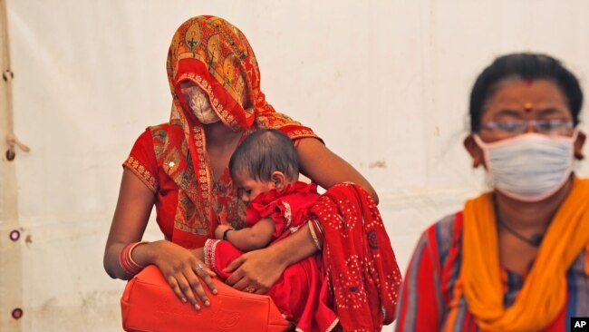 FILE - Women wait to receive the vaccine for COVID-19 in New Delhi, India, July 2, 2021.