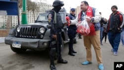 Des partisans du président égyptien Abdel Fattah al-Sissi donnant des fleurs aux policiers le 25 janvier 2016, lors de l'anniversaire du soulèvement populaire de 2011, sur la place Tahrir au Caire. (AP Photo/Amr Nabil)