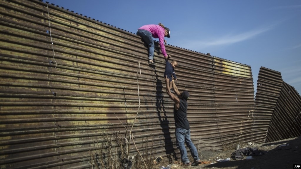 资料照： 一家中美洲人试图越过美墨边界在加州地段的边界墙。（2018年11月25日）(photo:VOA)