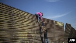 资料照： 一家中美洲人试图越过美墨边界在加州地段的边界墙。（2018年11月25日）