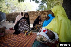 FILE - Relatives pay a condolence visit to the mother of one of the abducted students from the Government Girls Science and Technical College (GGSTC) in Dapchi, in Jumbam village, Yobe state, Nigeria, Feb. 24, 2018.
