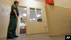  FILE - A Border Patrol agent stands inside one of the holding areas at the Tucson Sector of the U.S. Customs and Border Protection headquarters in Tucson, Ariz., Aug. 9, 2012.