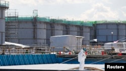 រូបឯកសារ៖ កម្មករ​ម្នាក់​ស្លៀក​សម្លៀក​បំពាក់​ការពារ​កំពុងកត់​ចំណាំ​នៅ​មុខ​អាង​ស្តុក​ទឹក​មានជាតិ​វិទ្យុសកម្ម​នៅ​រៀង​ចក្រ​ថាមពល​នុយក្លេអ៊ែ​ TEPCO ក្នុង​ក្រុង​ Okuma នៃទីក្រុង Fukushima ប្រទេស​ជប៉ុន។