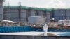 A worker, wearing protective suits and masks, takes notes in front of storage tanks for radioactive water at Tokyo Electric Power Co's (TEPCO) tsunami-crippled Fukushima Daiichi nuclear power plant in Okuma town, Fukushima prefecture, Japan, Feb.10, 2016.