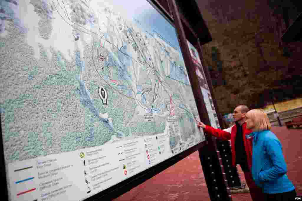 Visitors study the ski trail map of Rosa Khutor, which suffered from erratic snow cover and rain in February and March of this year. (V. Undritz for VOA)