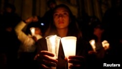 A supporter of the peace deal signed between the government and the Revolutionary Armed Forces of Colombia (FARC) rebels holds candles while attending a gathering at Bolivar Square during a "Silent March" in Bogota, Colombia, Oct. 5, 2016. 