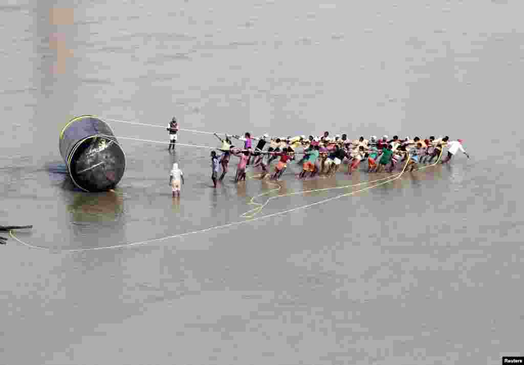 Laborers pull a pontoon to construct a temporary bridge for the Magh Mela festival on the river Ganges in Allahabad, India.