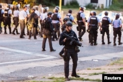 Police line up to block the street as protesters gathered after a black man was shot by police serving a search warrant in St. Louis, Missouri, Aug. 19, 2015.