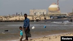 一名男子和他的兒子站在印度南部的泰米爾納德邦庫丹庫拉姆核電項目前的海灘。