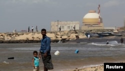 FILE - A man stands with his son on the beach near the Kudankulam nuclear power project in the southern Indian state of Tamil Nadu. 