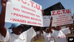 FILE: Members of the Zimbabwe Congress of Trade Unions hold banners advocating the scrapping of taxes on pension benefits. (AP Photo)