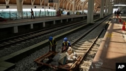 FILE - Workers transport building materials at the construction site of Halim Station ahead of a test run of the Jakarta-Bandung high-speed train, in Jakarta, Indonesia, Aug. 12, 2023. The first high-speed rail service in Southeast Asia is part of China's Belt and Road Initiative