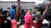 Russian punk group Pussy Riot members Nadezhda Tolokonnikova, in the blue balaclava, and Maria Alekhina, in the pink balaclava, make their way through a crowd after they were released from a police station, Feb. 18, 2014, in Adler, Russia.