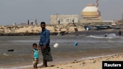 FILE - A man stands with his son on the beach near the Kudankulam nuclear power project in the southern Indian state of Tamil Nadu. 