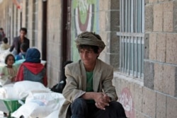 FILE - A boy waits for food supplies provided by the World Food Program at a school in Sanaa, Yemen, Aug. 25, 2019.