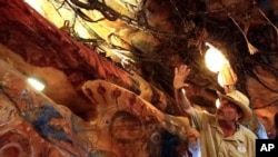 In this April 29, 2017 photo, Joe Rohde, design and production leader for Pandora-World of Avatar land attraction, explains about the caverns and the meaning of the cave drawings of the Na'vi, the native inhabitants of the planet Pandora at Disney's Animal Kingdom theme park at Walt Disney World in Lake Buena Vista, Florida. 