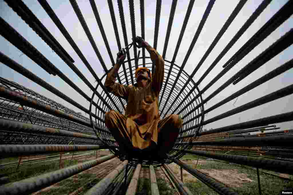 A worker ties steel bars at a construction site for a road in Peshawar, Pakistan, March 27, 2018.