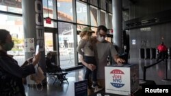 La pandemia del coronavirus está marcando las elecciones presidenciales de EE.UU. En la foto, un elector con mascarilla coloca su boleta en la votación anticipada en la ciudad de Nueva York el 24 de octubre de 2020.