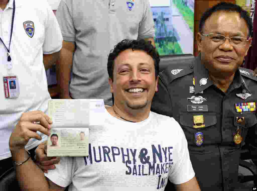 Italian Luigi Maraldi, left, whose stolen passport was used by a passenger boarding a missing Malaysian airliner, shows his passport as he reports himself to Thai police Lt. Gen. Panya Mamen, right, at Phuket police station in Phuket province, southern Thailand, March 9, 2014.