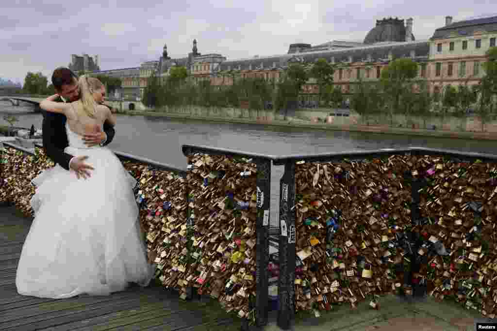 Dominika and Bartek Mieczkowski, A recently-married couple from Poland, embrace near grills covered with &quot;love locks&quot; on a walkway which leads to the Pont de Arts over the River Seine in Paris, France.