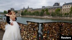 Pasangan yang baru menikah dari Polandia, Dominika dan Bartek Mieczkowski, berpelukan dekat pagar jembatan yang dipenuhi dengan gembok cinta di jembatan menuju Pont de Arts di sungai Seine di Paris, Perancis (31/5).