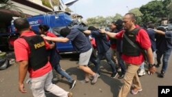FILE - Police officers escort men arrested in a raid on a gay sauna at North Jakarta police headquarters in Jakarta, Indonesia, May 22, 2017. Authorities in Indonesia's West Java province announced the creation of a task force charged with investigating activities by gays.