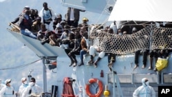FILE - Migrants wait to disembark from the Italian Navy vessel "Chimera" in the harbor of Salerno, Italy, April 22, 2015. 
