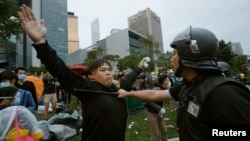 A pro-democracy protester blocks a riot policeman during a clash outside the government headquarters in Hong Kong, December 1, 2014.