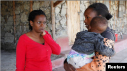 FILE - Serene Haven secondary school founder Elizabeth Wanjiru talks to Josephine Wanjiru, 19, who carries her child outside a dormitory at the Serene Haven secondary school, accommodating pregnant girls and teenage mothers with their babies in Nyeri, Kenya January 20, 2021.