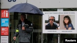 Une affiche avec les portraits du journaliste Ghislaine Dupont, à droite, 51 ans, et le technicien radio Claude Verlon, 58 ans, deux français tués au Mali, est aperçue à l'entrée du bâtiment de Radio France Internationale à Issy-les-Moulineaux près de Paris, le 5 novembre 2013.