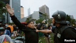 Un manifestante pro democracia bloquea a un policía antimotines en las afueras de la sede del gobierno en Hong Kong.