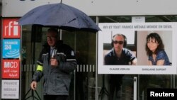 A poster with the portraits of reporter Ghislaine Dupont (R), 51, and radio technician Claude Verlon, 58, two French journalists killed in Mali last week, is seen at the entrance of Radio France International building near Paris on November 5, 2013. 