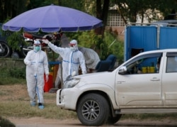 FILE - Health workers arrive to collect at a drive-through testing and screening facility for the coronavirus, in Islamabad, Pakistan, June 6, 2020.