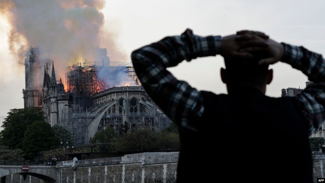 Warga yang berada di dekat lokasi kebakaran Katedral Notre Dame bersedih atas musibah yang menimpa salah satu ikon kota Paris ini, Senin (15/4). 