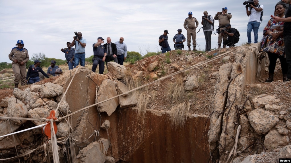 FILE - People watch as Senzo Mchunu, South African police minister (not pictured), inspects outside the mineshaft where it is estimated that illegal miners are believed to be hiding underground, in Stilfontein, Nov. 15, 2024.