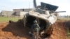 A rebel fighter walks near a military vehicle in Menagh, north of Aleppo, Syria, Dec. 2, 2024. 