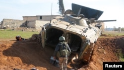 A rebel fighter walks near a military vehicle in Menagh, north of Aleppo, Syria, Dec. 2, 2024. 