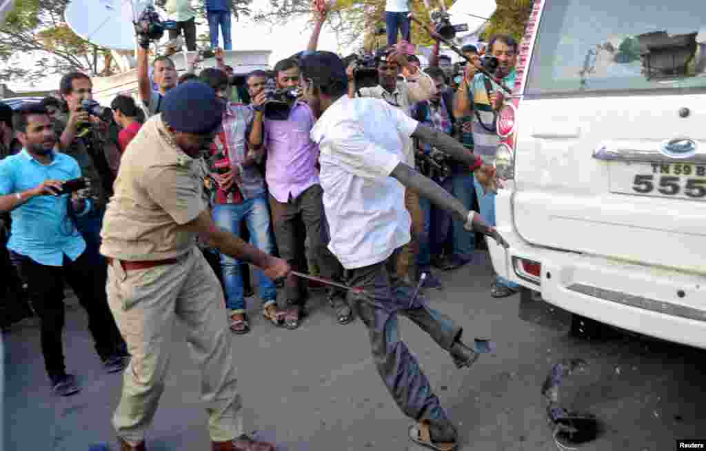 Seorang polisi menggunakan tongkat kayu untuk membubarkan massa, saat V. K. Sasikala (tidak tampak) salah seorang pejabat Tamil Nadu menyerahkan diri di Bengaluru, India.