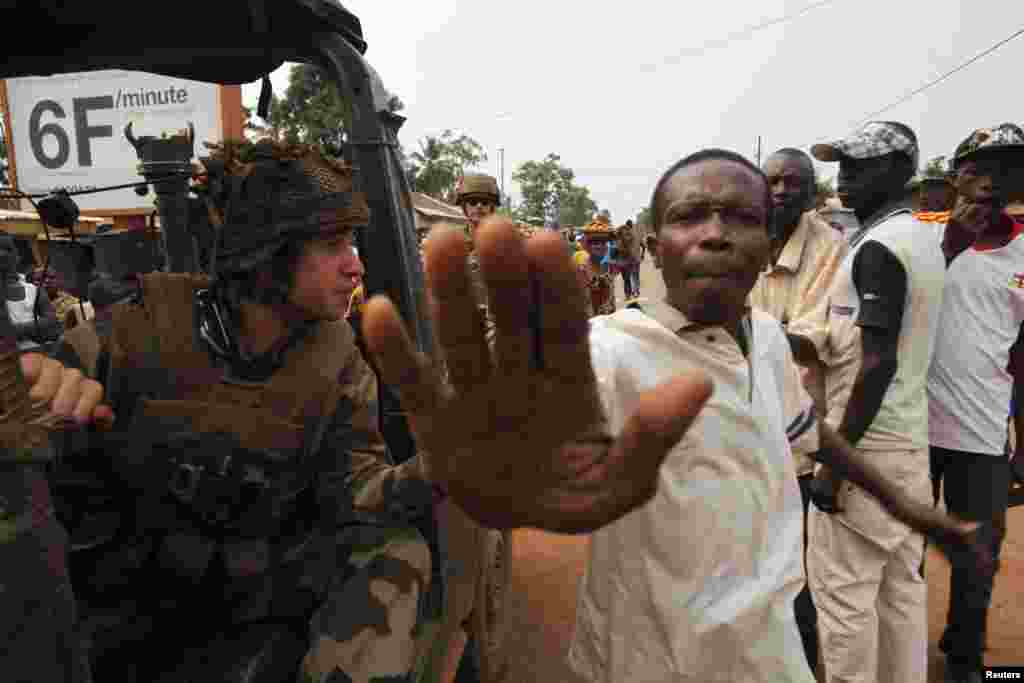 A man tries to prevent a photographer from taking pictures as angry young men argue with French soldiers in patrol in the pro-Christian area of Bangui, Feb. 15, 2014. 