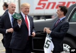 FILE - Wisconsin Gov. Scott Walker, right, presents President Donald Trump with a Milwaukee Buck basketball hat and jersey as he arrives in Kenosha, Wisconsin, April 18, 2017.