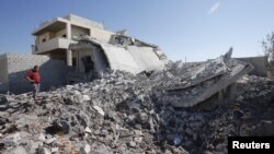 Civilians stand near a destroyed house in wake of early morning Syrian Air Force strikes, Aziz, Sept. 3, 2012.