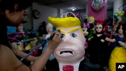 FILE - Alicia Lopez Fernandez paints a pinata depicting Donald Trump at her family's store "Pinatas Mena Banbolinos" in Mexico City, July 10, 2015. In a surprise move, Donald Trump will travel to Mexico Aug. 31 to meet with President Enrique Pena Nieto.